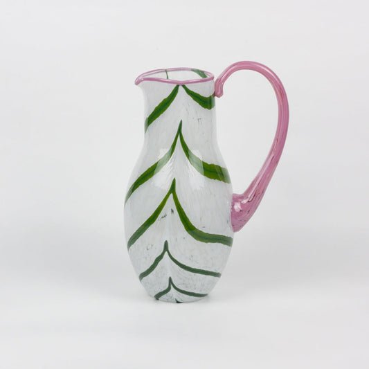 Ceramic pitcher with green leaf patterns and pink handle on a white background