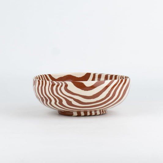 Ceramic bowl with brown and white striped pattern on a white background